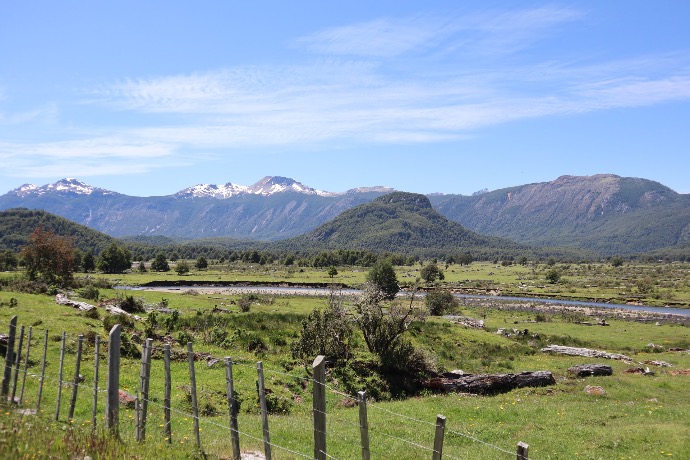 green grass field near mountain under blue sky during daytime