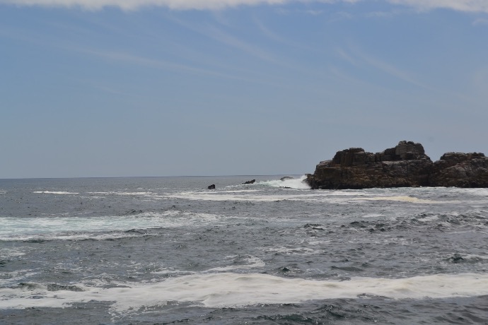 rock formation in ocean under blue sky