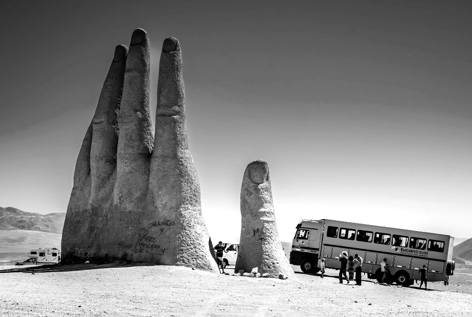 people sitting on brown sand near yellow bus during daytime